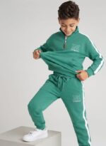 Băiat îmbrăcat într-un compleu sport verde mentă pentru copii, realizat din 90% bumbac și 10% elastan.