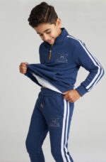 Băiat îmbrăcat într-un compleu sport albastru pentru copii, realizat din 90% bumbac și 10% elastan.